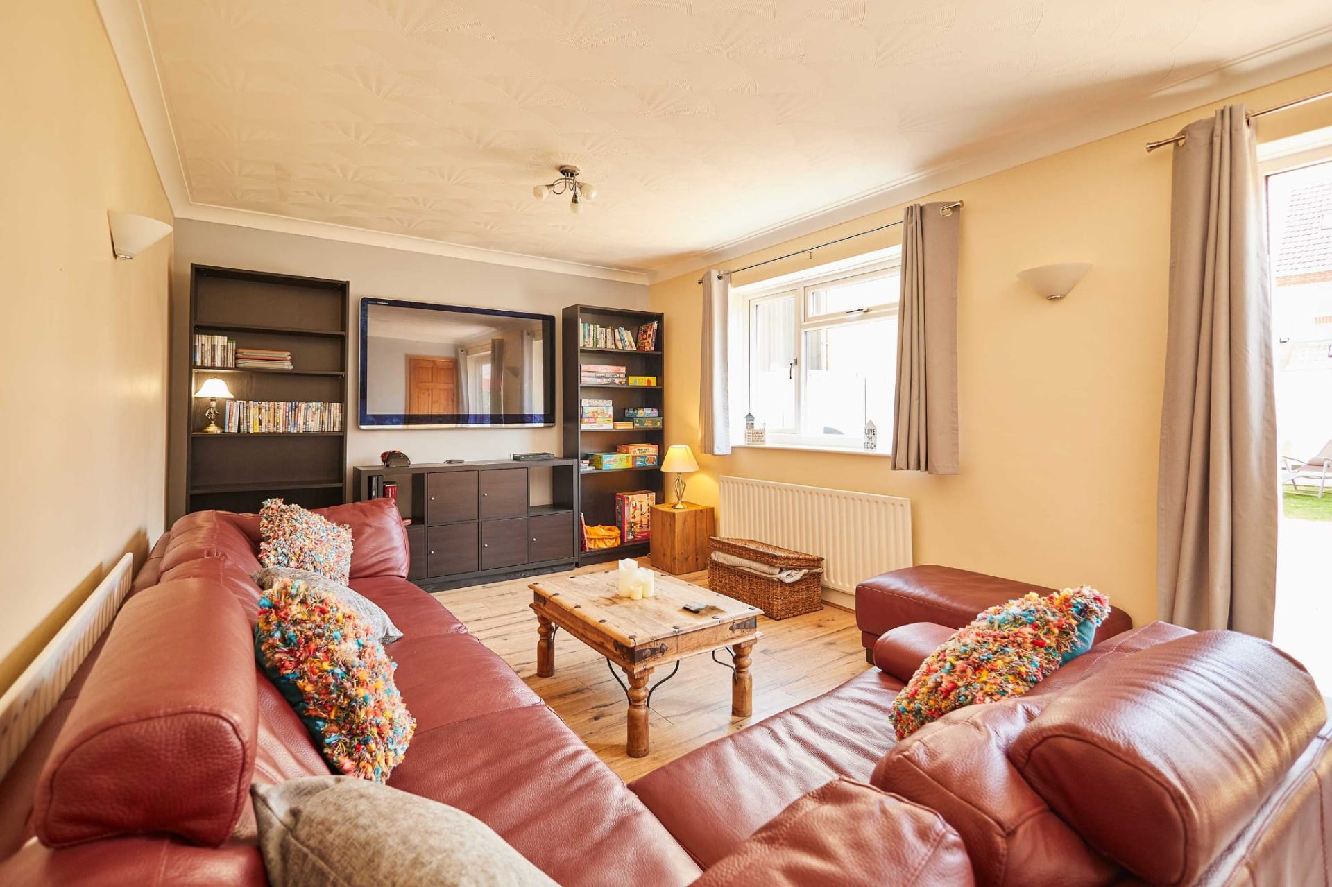 Bright living room with red leather sofas and bookshelves at Sandcastle House